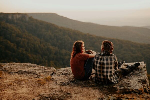 Couple together on rock overlooking mountains.