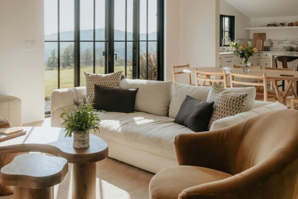 Living area with plush seating, modern kitchen, and large windows.