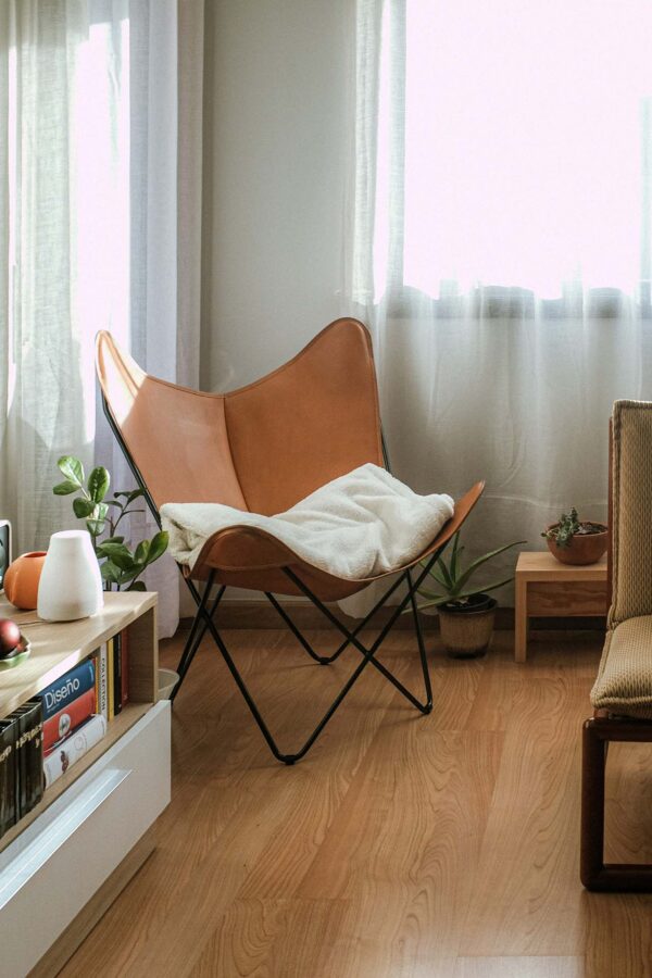 Apartment living room with folding leather chair and console with books.