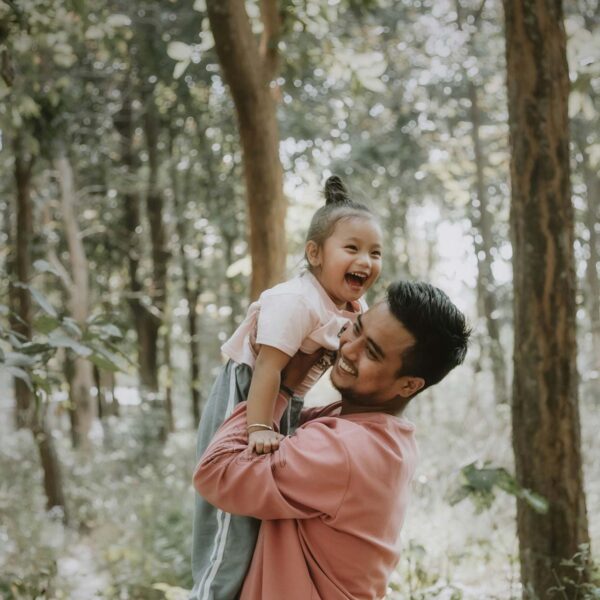Young parent and child playing together in the forest.