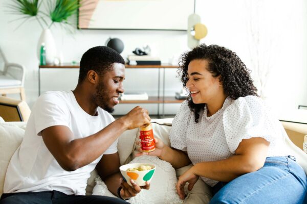 Friends sitting together eating a meal on a couch.