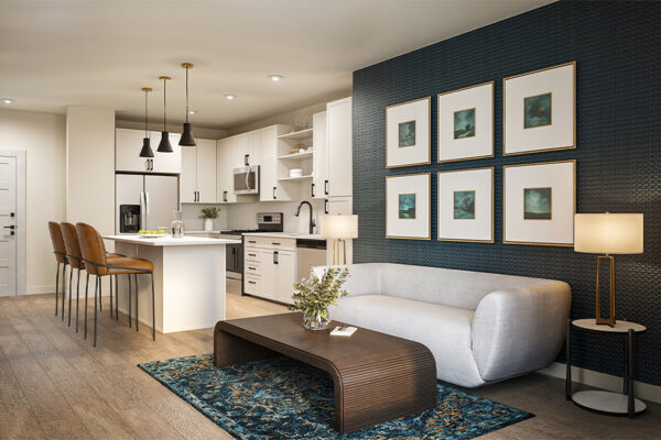Interior rendering of a modern apartment showing a white kitchen with a breakfast bar and leather stools, adjacent to a living room with a gray sofa, dark textured wall with six framed art pieces, and a decorative blue rug.